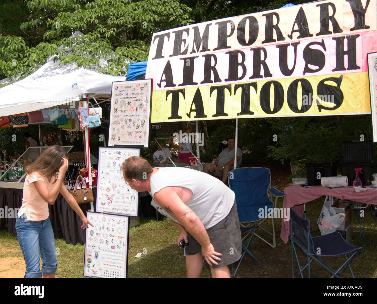 Weißes Paar, das sich für ein Tattoo-Design bei einem Outdoor-Festival in South Carolina, USA, entscheidet. Stockfoto