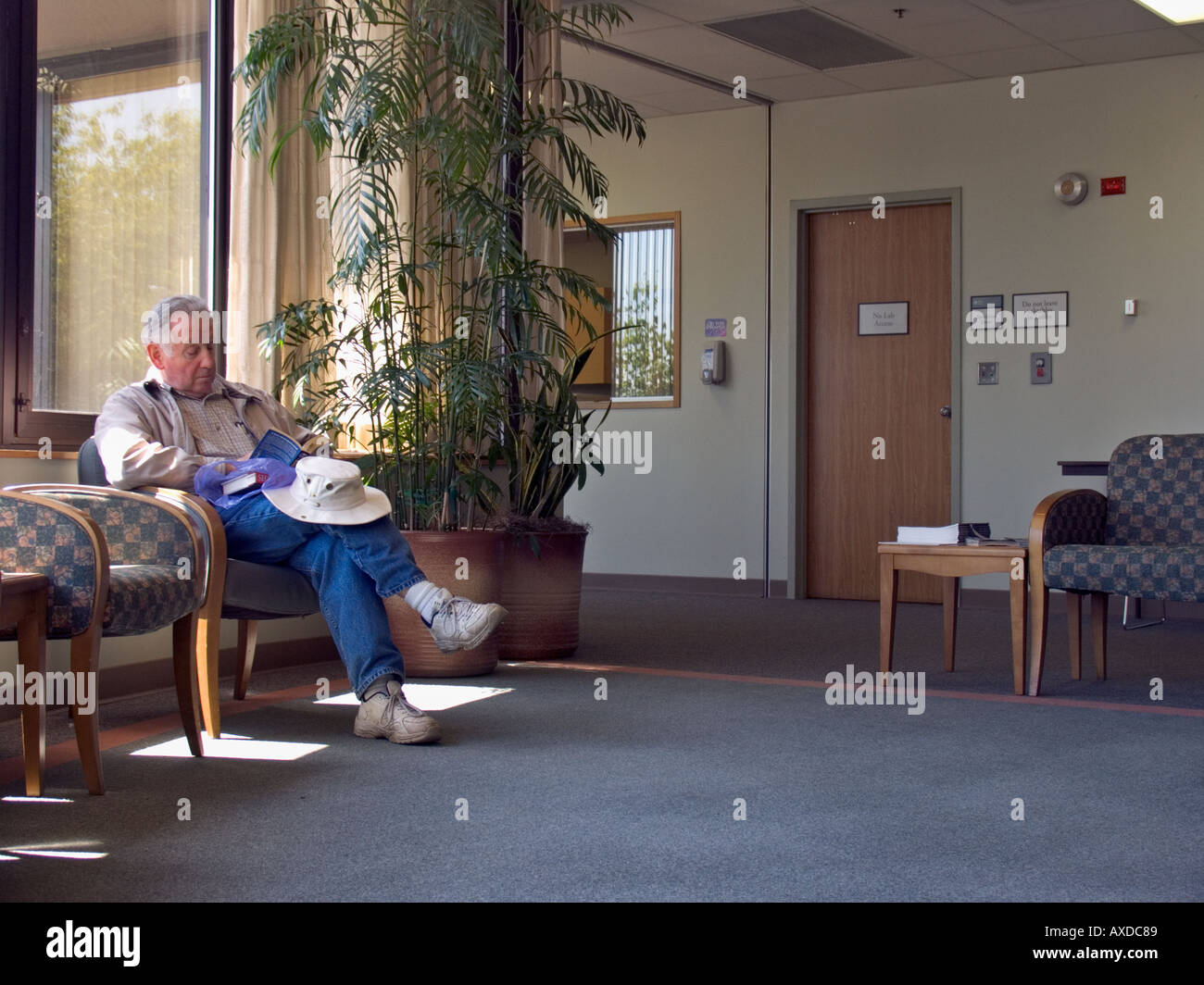 Mann liest Buchveröffentlichung im Krankenhaus Wartebereich keine Stockfoto