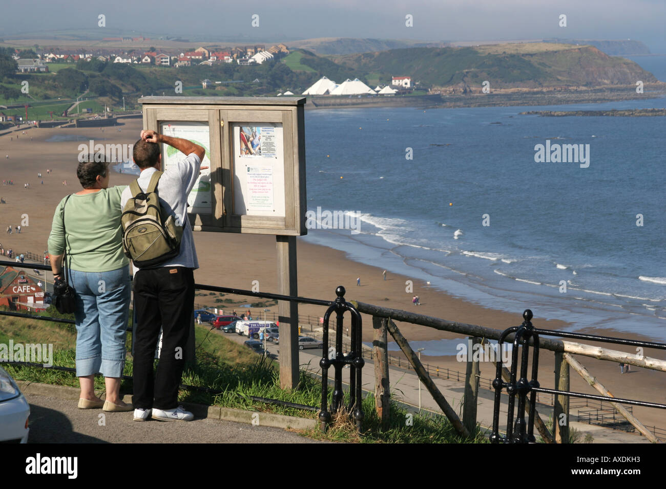 Paar auf der Suche an einem Ort anzeigen mit Blick auf die North Bay in Scarborough, North Yorkshire Karte Stockfoto