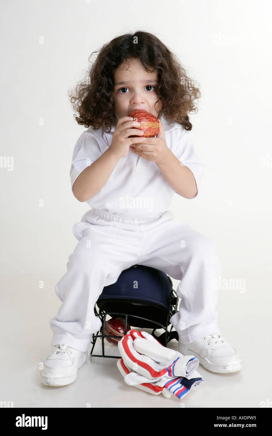 Bildnis eines Knaben tragen Cricket Uniform und Essen Apfel Stockfoto