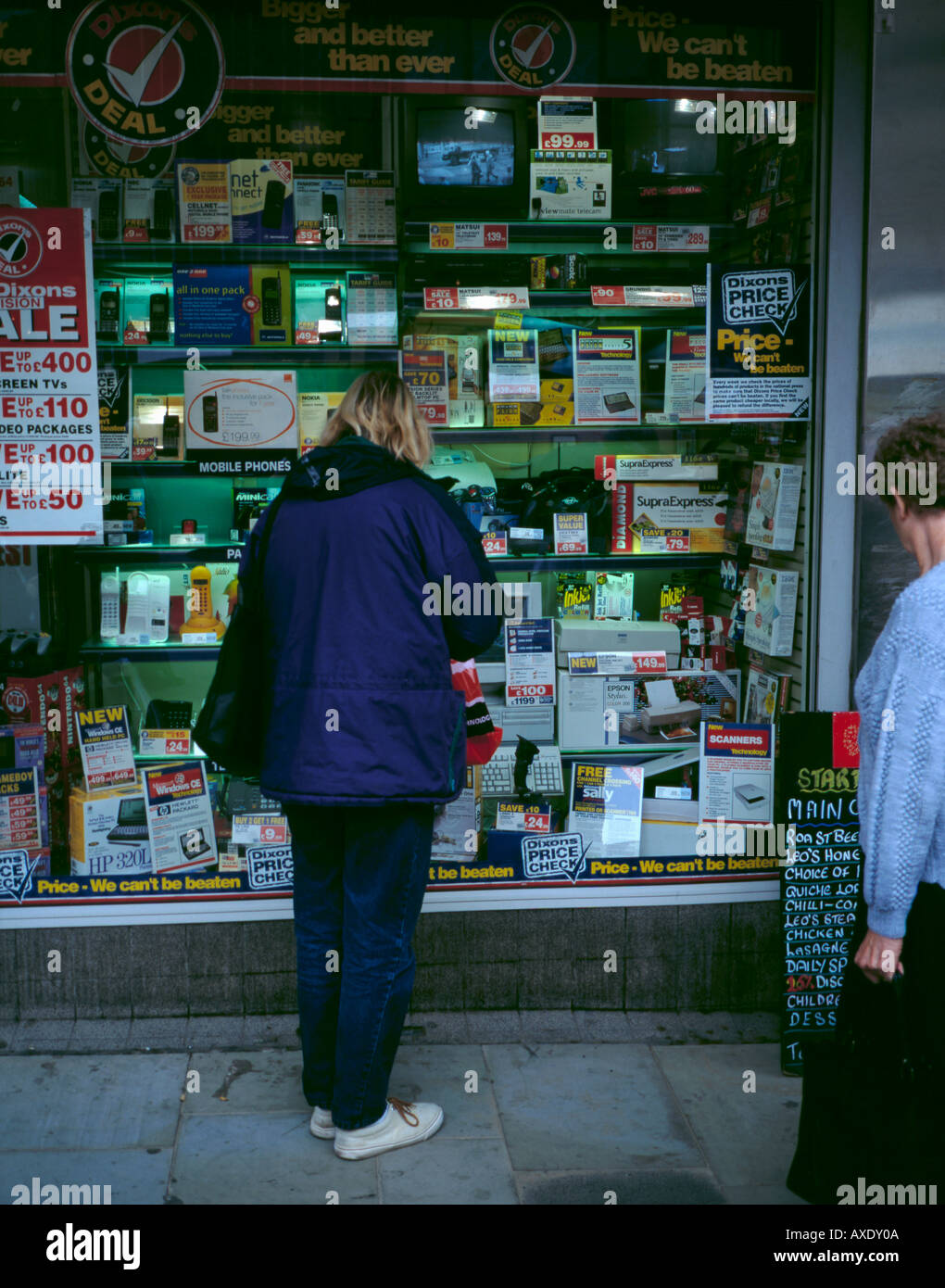 Frau an einem Schaufenster voller elektrischer Verbraucher Waren zum Verkauf suchen, Newcastle upon Tyne, Tyne and Wear, England, UK. Stockfoto