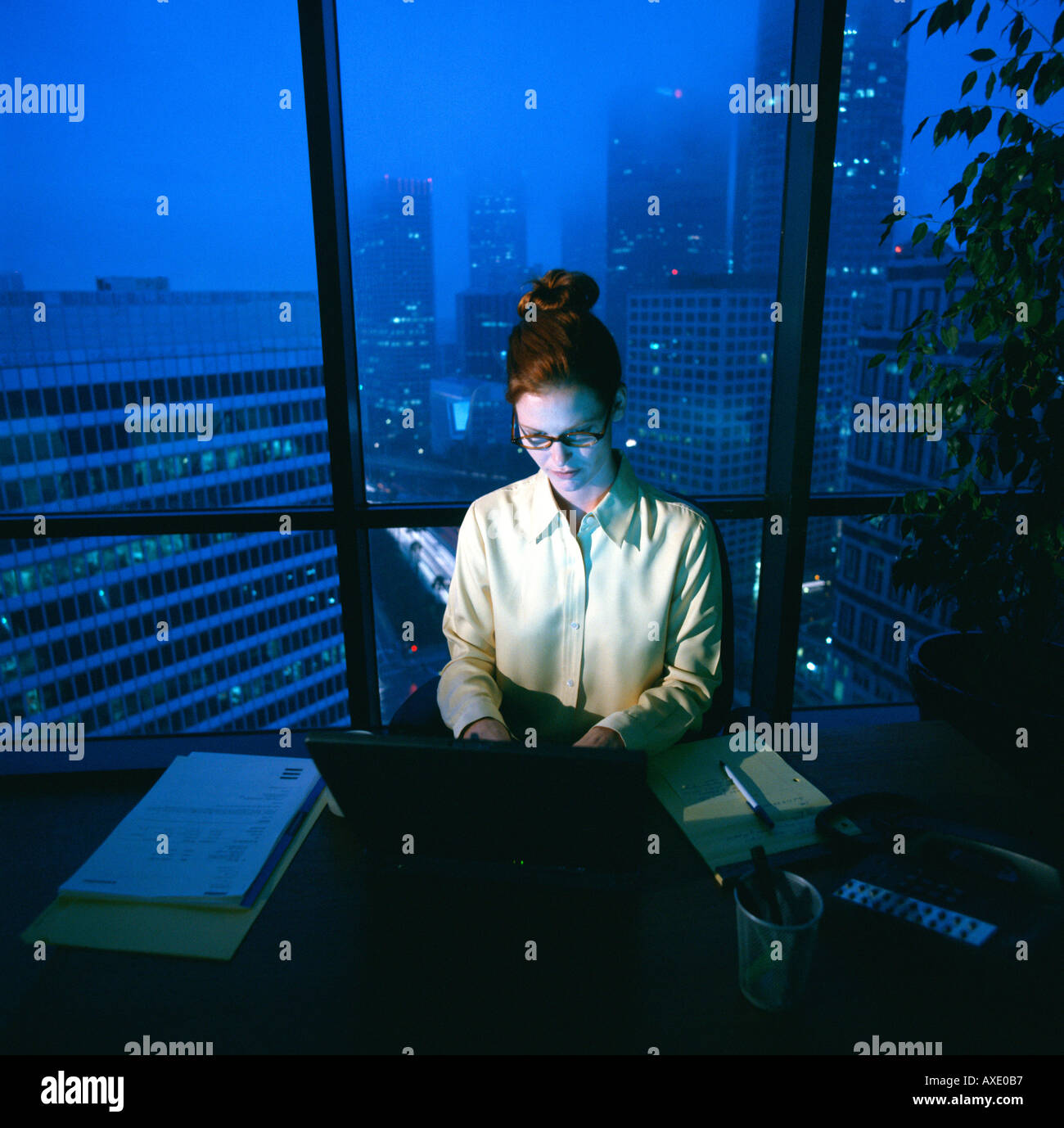 Weibliche Führungskraft arbeitet nach Stunden am Schreibtisch Stockfoto