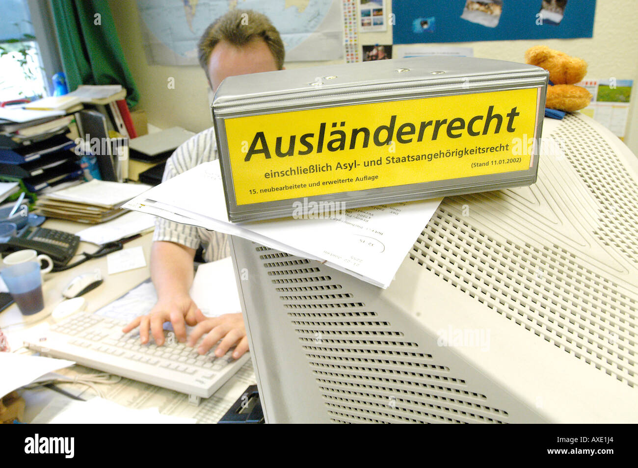 Schreiber-Exekutive in sein Büro hinter seinem Computer. Buch: Immigrantion Gesetze Stockfoto