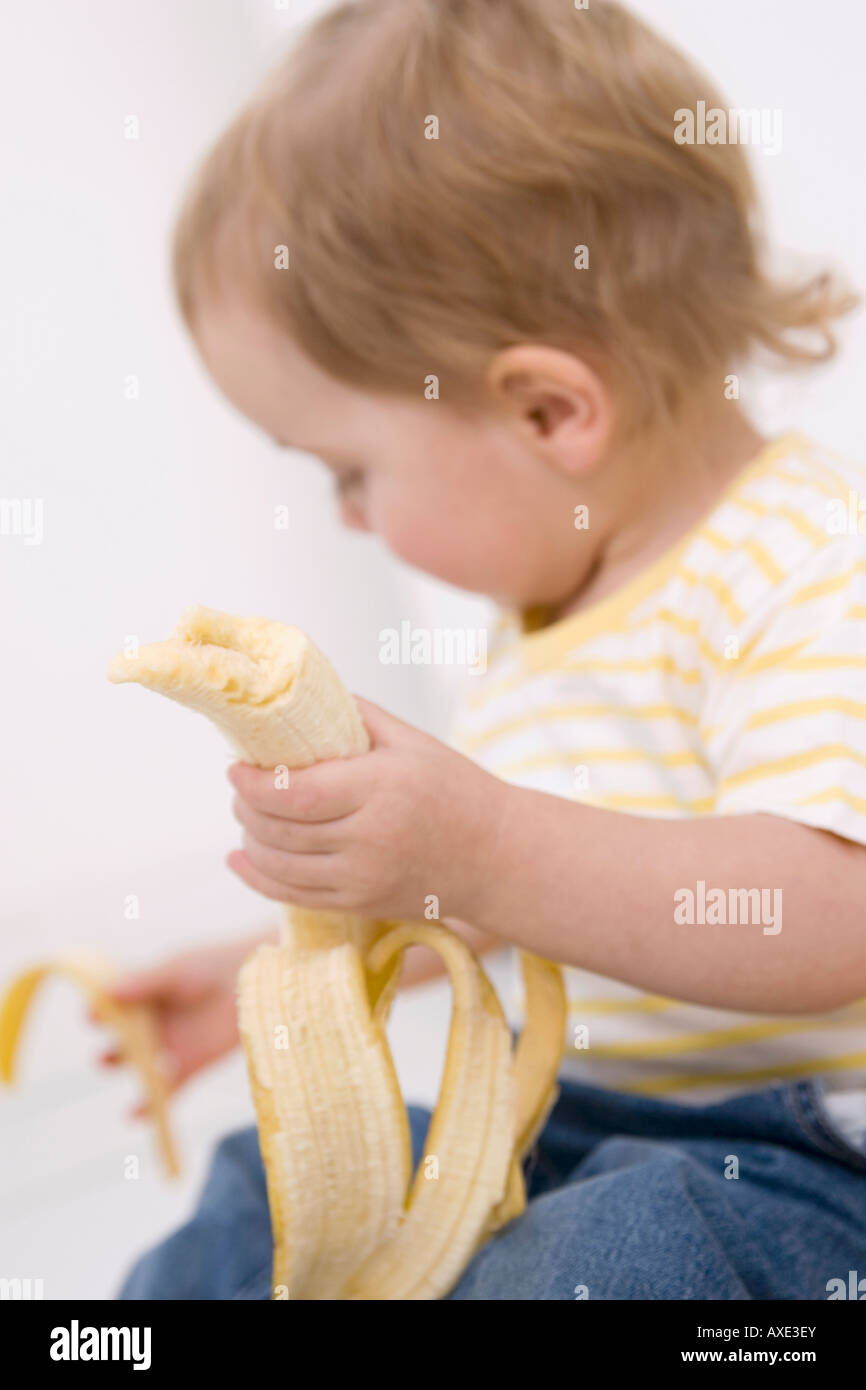Babymädchen (2-3) eine Banane schälen Stockfoto