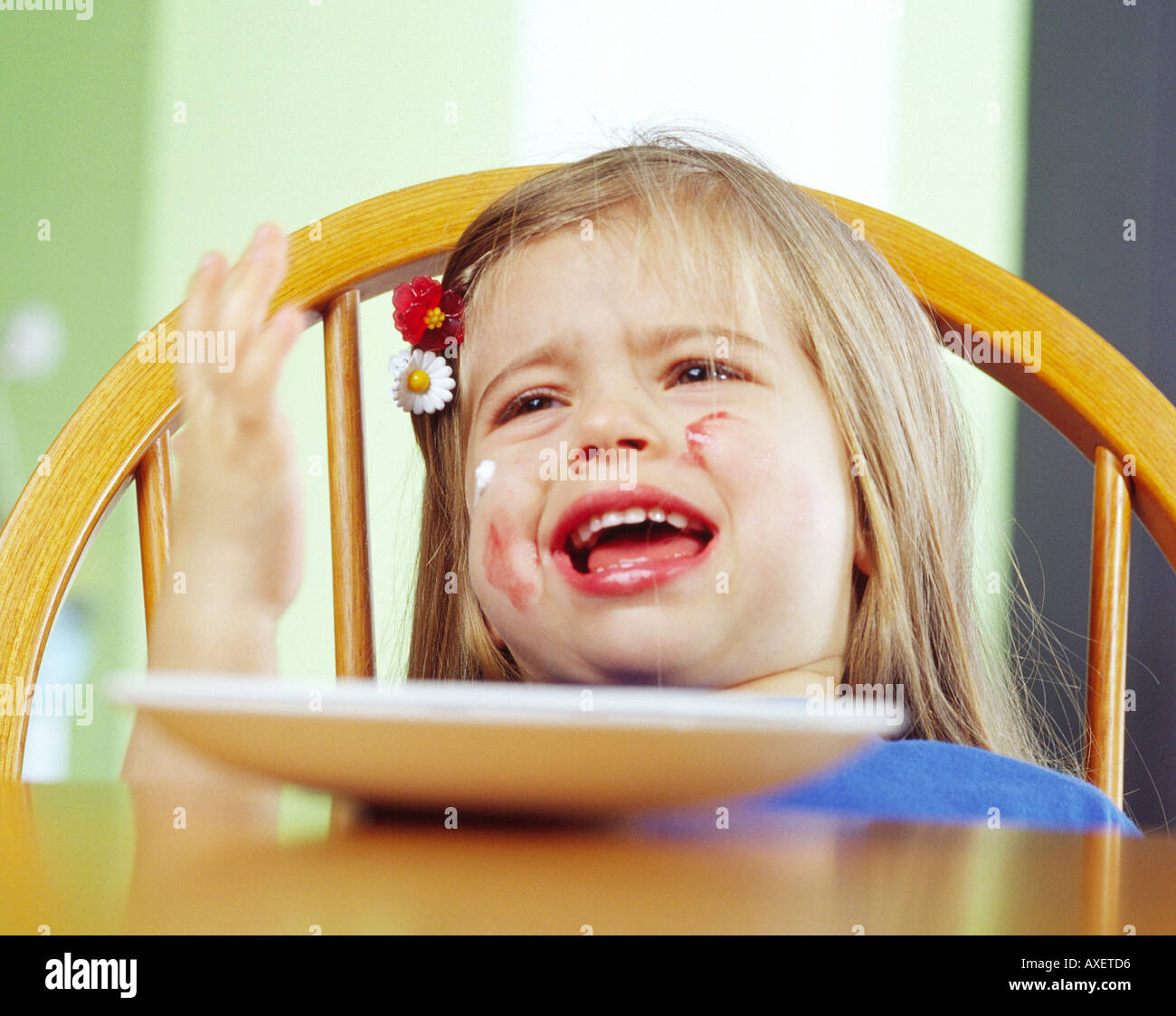 Mädchen weiblich Alter 0-5 Kind Kindheit Kind Kapuze fair haired blonde Schrei Schrei Schrei Essen sitzen Fleck Platte Stuhl traurig ich Unzufriedenheit Stockfoto