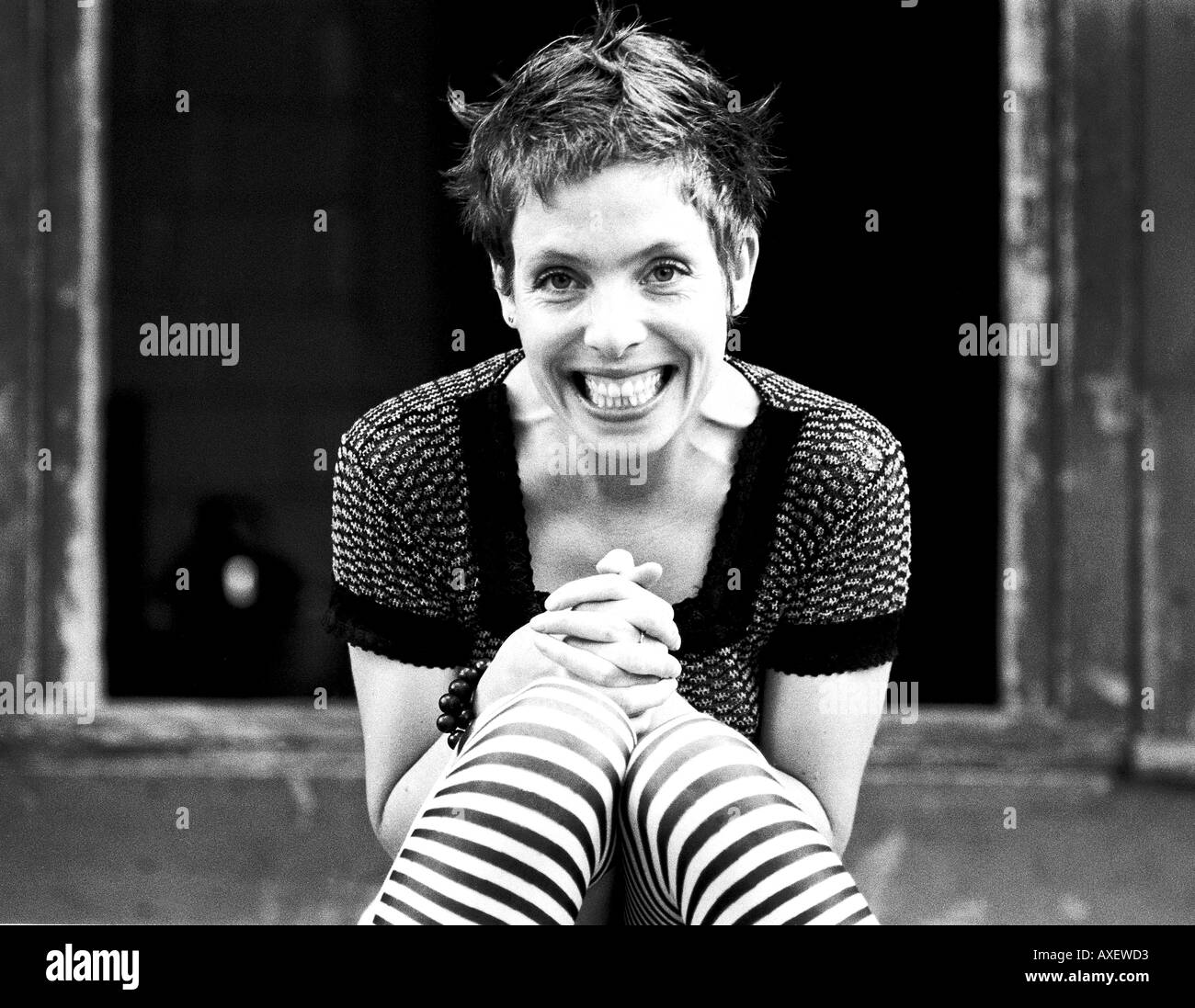 Frau weiblich Alter 30 35 Erwachsenen slim fit blonde fair haired Lächeln Lächeln Lachen Sit Spange Hände Finger Socken Streifen fröhlich j Stockfoto