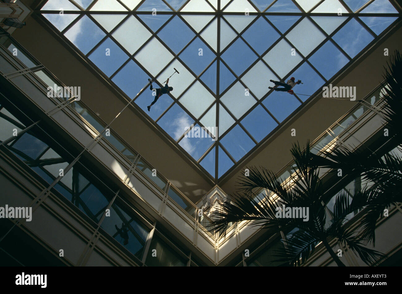 Zwei Fensterreiniger baumeln hoch oben ein Bürogebäude Atrium in der City of London Stockfoto