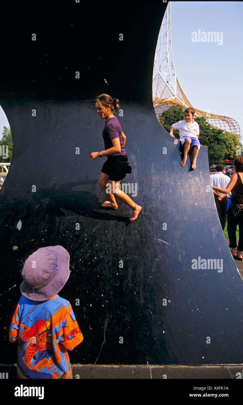 Kinder spielen am vorwärts Surge Skulptur Victorian Arts Centre Rasen Melbourne Victoria Australien vertikale Stockfoto