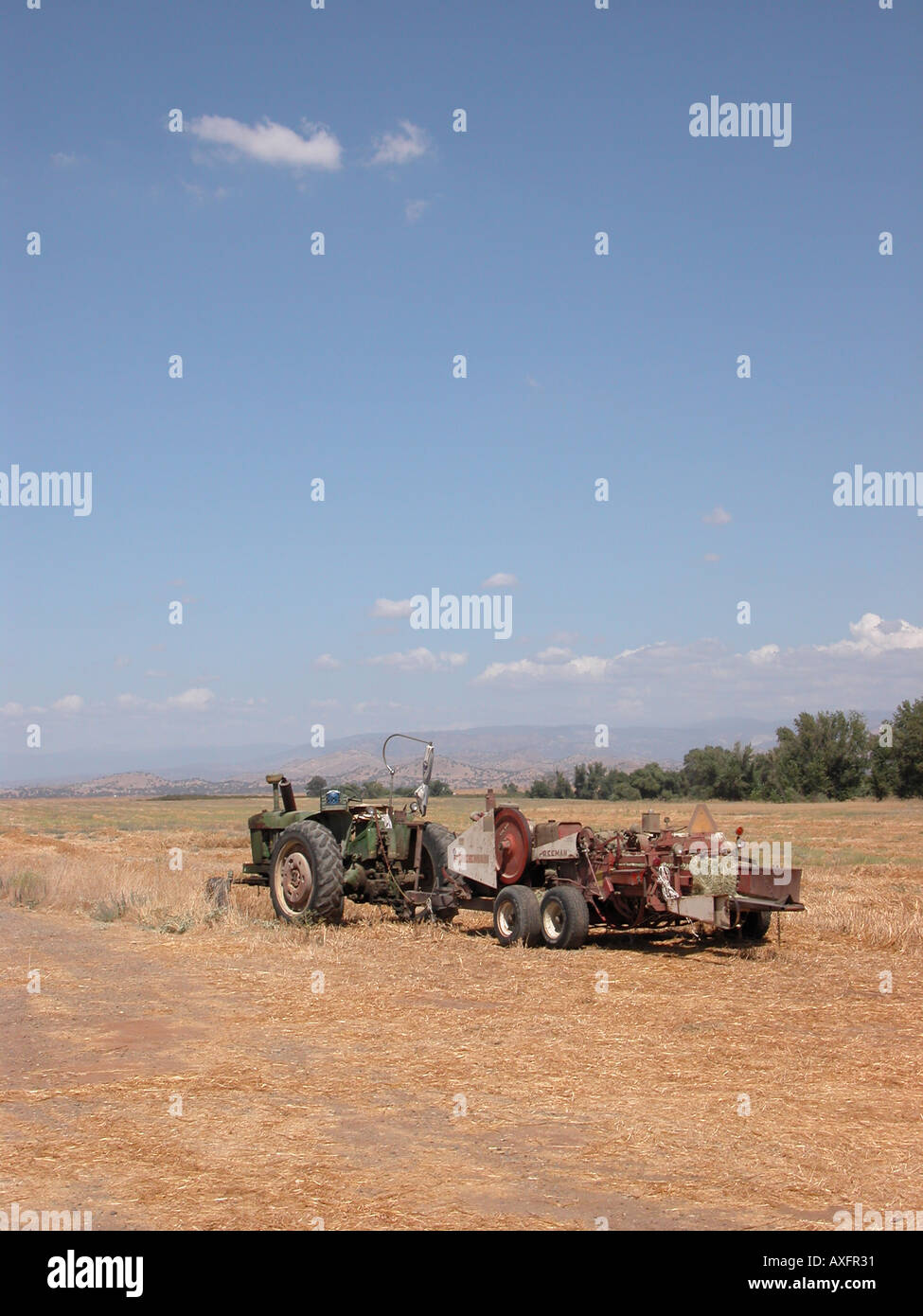 Heu-Ballenpresse und Traktor auf einem Bauernhof in Zentral-Kalifornien Stockfoto