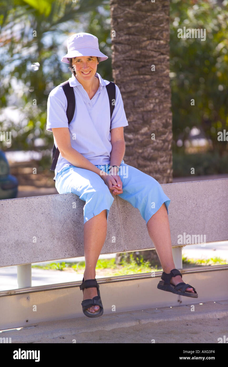 SPANIEN IBIZA PORT DES TORRENT 40 JAHRE ALTE FRAU FRAU MIT HUT SHORTS SANDALEN RUCKSACK SIGHTSEEING SITZEN AUF WAND TOURISMUS REISEN ORTE LAGE URLAUB URLAUB PAUSE RUHE ENTSPANNUNG SPAß AKTIVITÄT REISEVERANSTALTER Stockfoto
