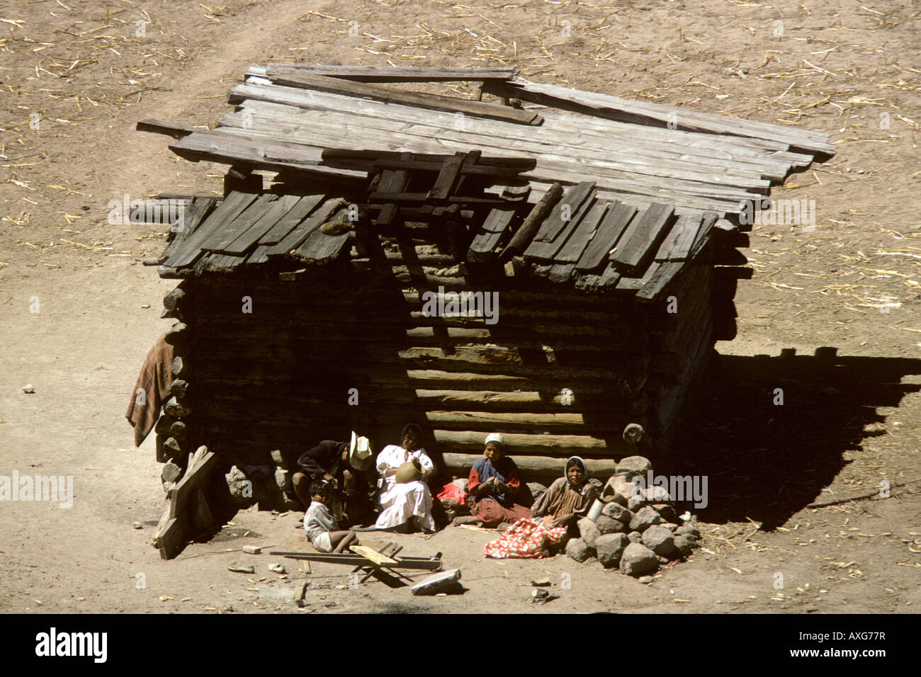 Mexiko. Einfache Blockhütte in der hohen Sierra Tarahumara. Familie der Indianer sitzen vor, einige tun Hausarbeiten Stockfoto
