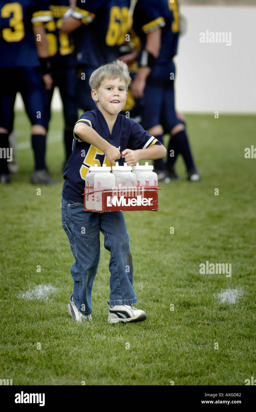 7 Jahre alten Jungen dient als Wasser junge Helfer während ein High-School-Fußball-Wettbewerb Stockfoto