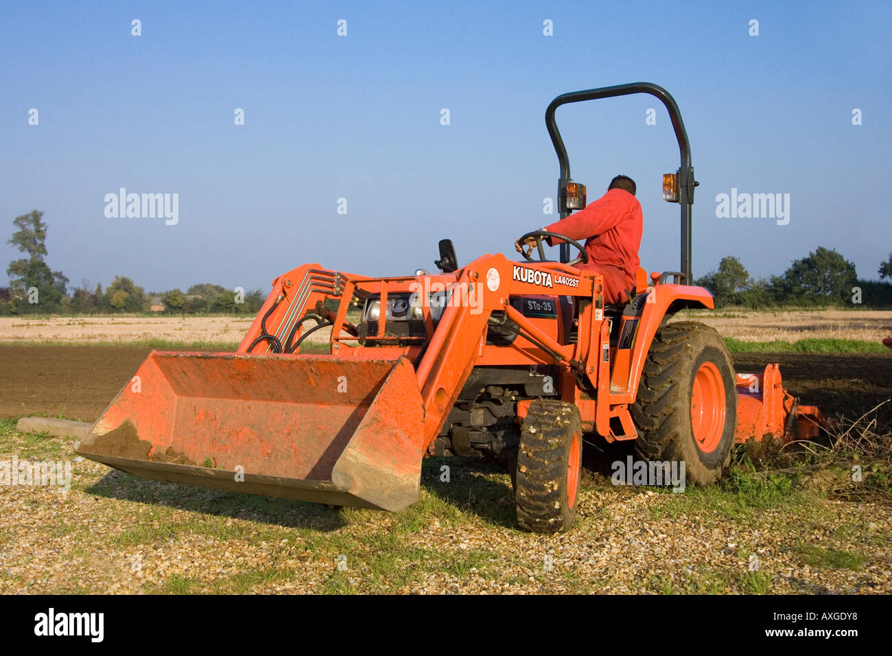 ein Traktor zur Ebene und Entfernen von Steinen aus dem Boden in Vorbereitung Pflanzung Grassamen Stockfoto