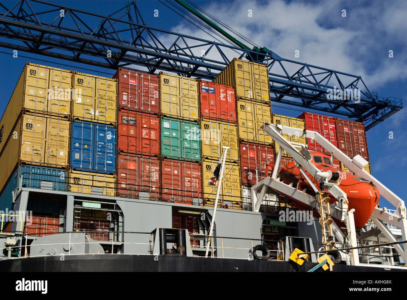 Stapel von Containern auf dem Achterdeck eines Containerschiffes mit einem Kran-Boom-Overhead. Stockfoto