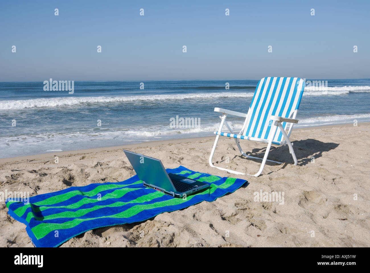 Eine Strand Büro umfasst ein Laptop-Stuhl und Strand-Handtuch Stockfoto