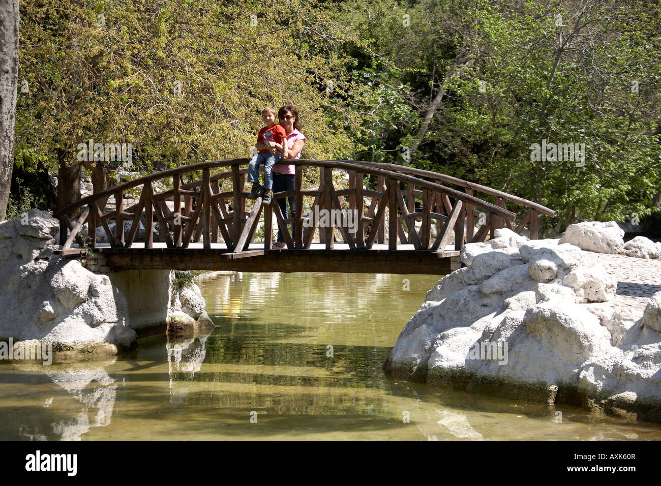Kleiner junge Kind und Frau Mutter auf Brücke über den Teich im Frühjahr in nationale Gärten Athen oder Athini Griechenland Stockfoto
