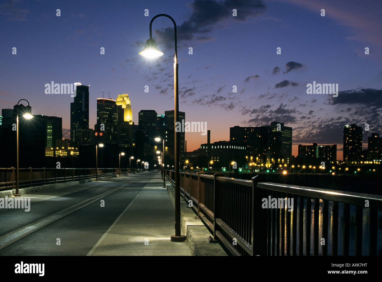 JAMES J. HILL STONE ARCH BRIDGE ÜBERQUERT DEN MISSISSIPPI RIVER.  MINNEAPOLIS, MINNESOTA SKYLINE IM HINTERGRUND.  EINBRUCH DER DUNKELHEIT. Stockfoto