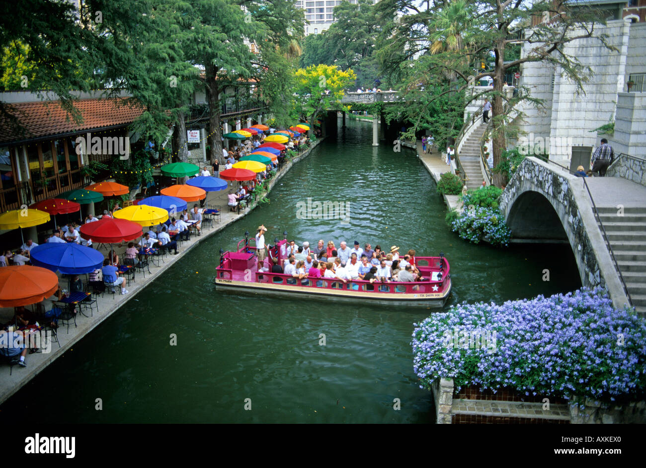 Besucher auf einer Bootstour und Menschen, die Restaurants und Bars entlang der River Walk in San Antonio, Texas Stockfoto