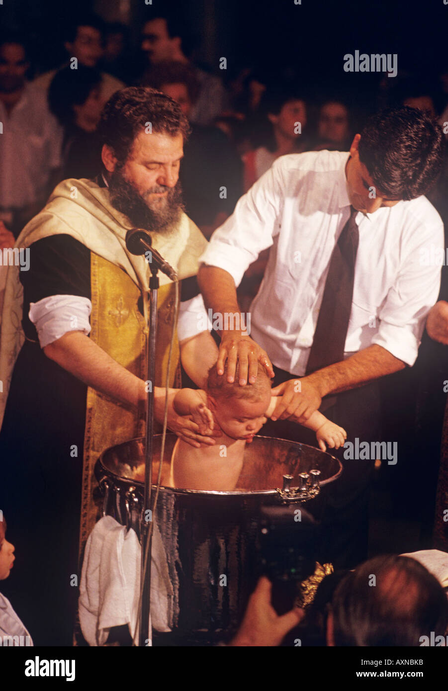 In der Taufe in der griechisch-orthodoxen Kirche wird Wasser über den Kopf des Kindes gegossen und es ist in Wasser eingetaucht. Stockfoto