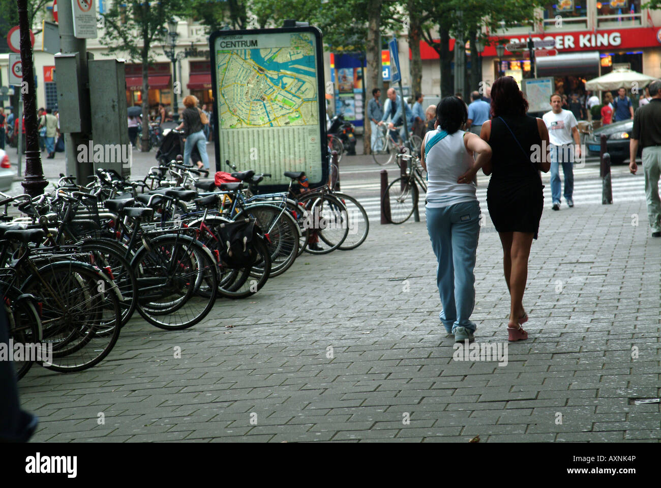 Eine Straße in Amsterdam mit Bikes oder Fahrräder eingesperrt entlang es und Straßenmusiker spielen Stockfoto
