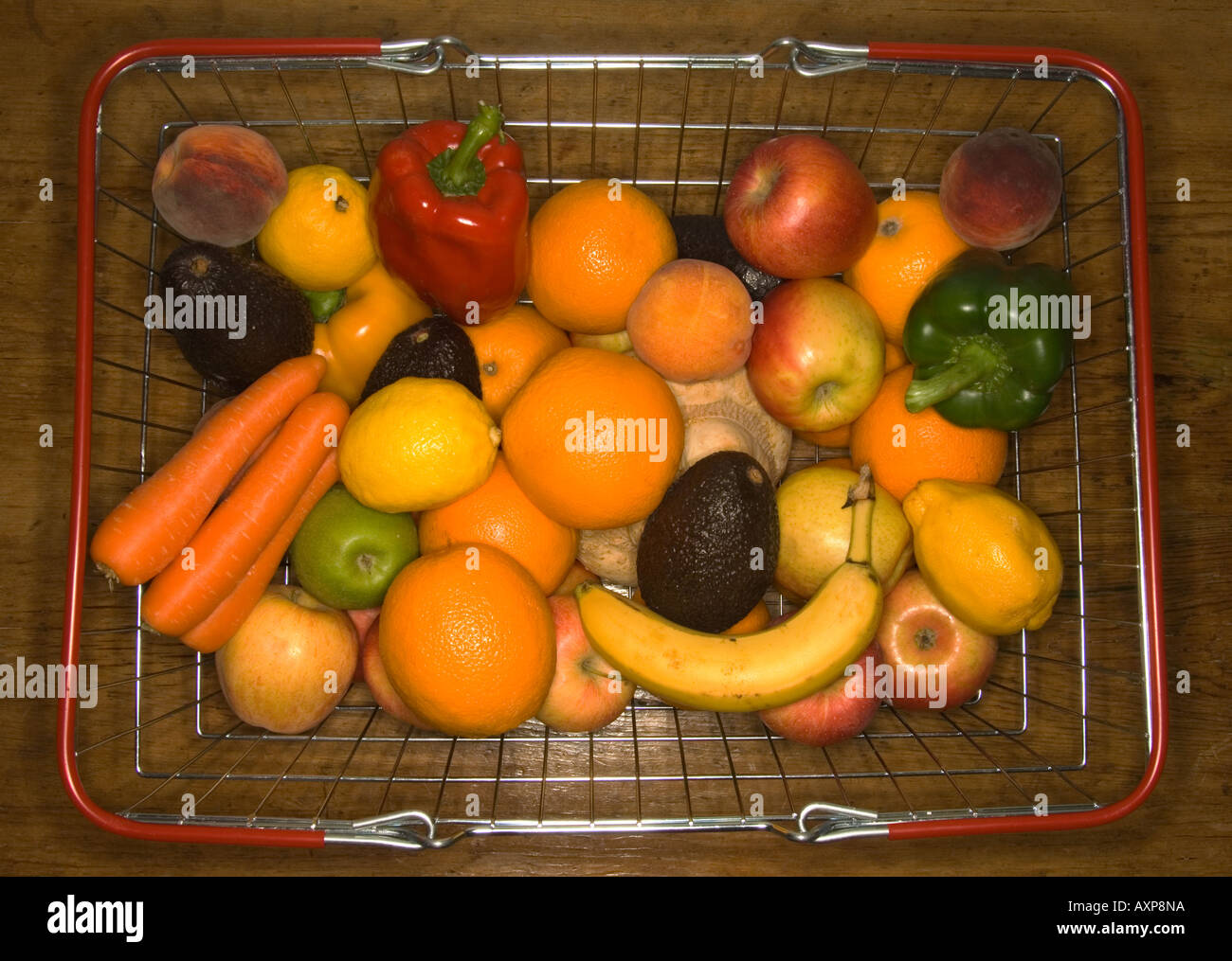 Supermarkt-Korb voller Obst und Gemüse auf hölzernen Tischplatte Stockfoto