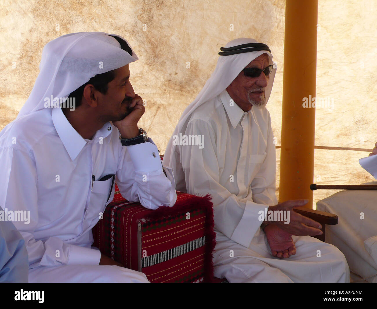 Katarische Männer in traditioneller Kleidung sitzen und plaudern in der Marina von Doha. Stockfoto