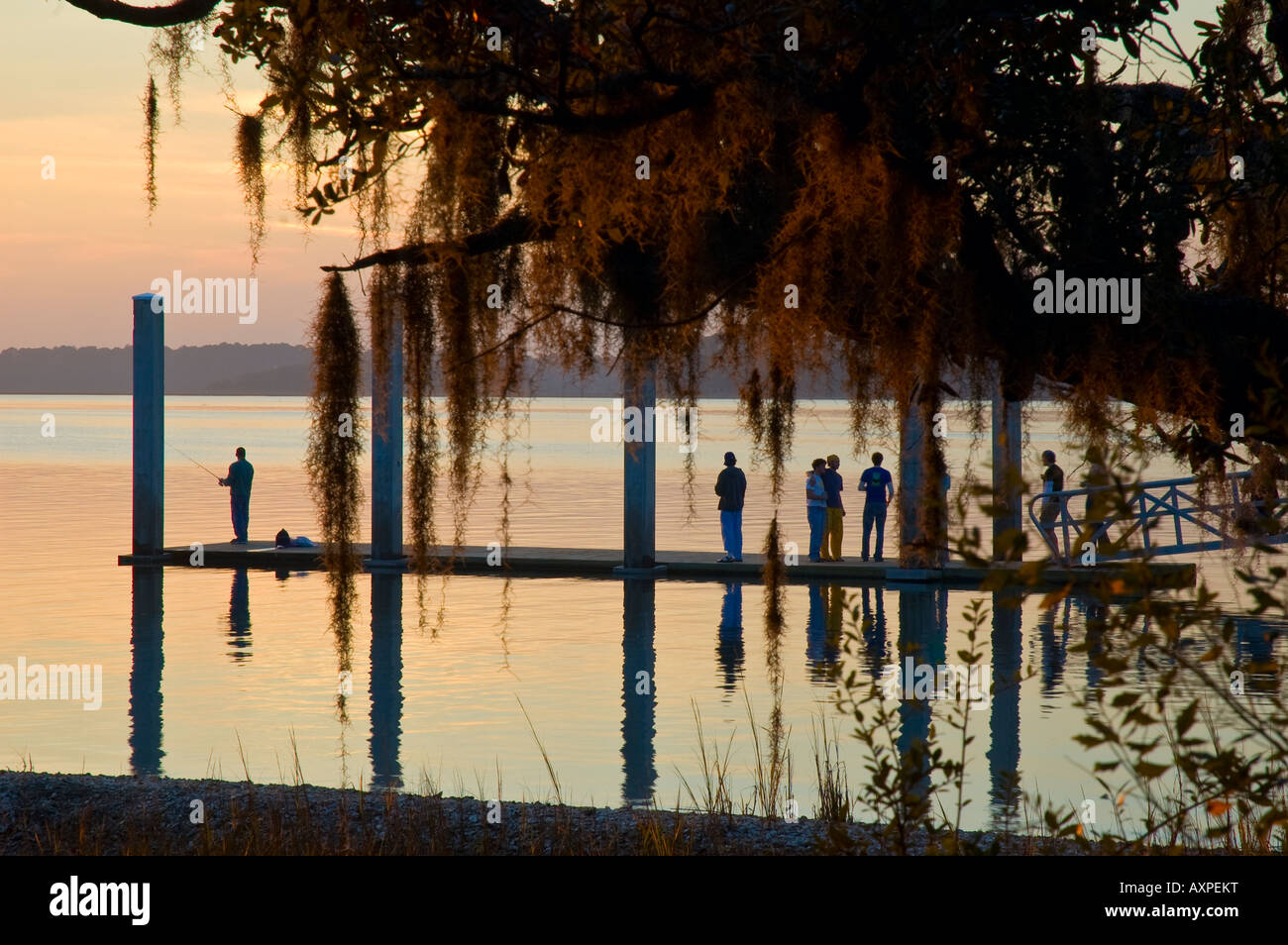 Gruppe von Touristen und einsamen Fischer stehen auf Promenade während des Sonnenuntergangs in der Nähe von Hilton head South Carolina Vereinigte Staaten von Amerika Stockfoto