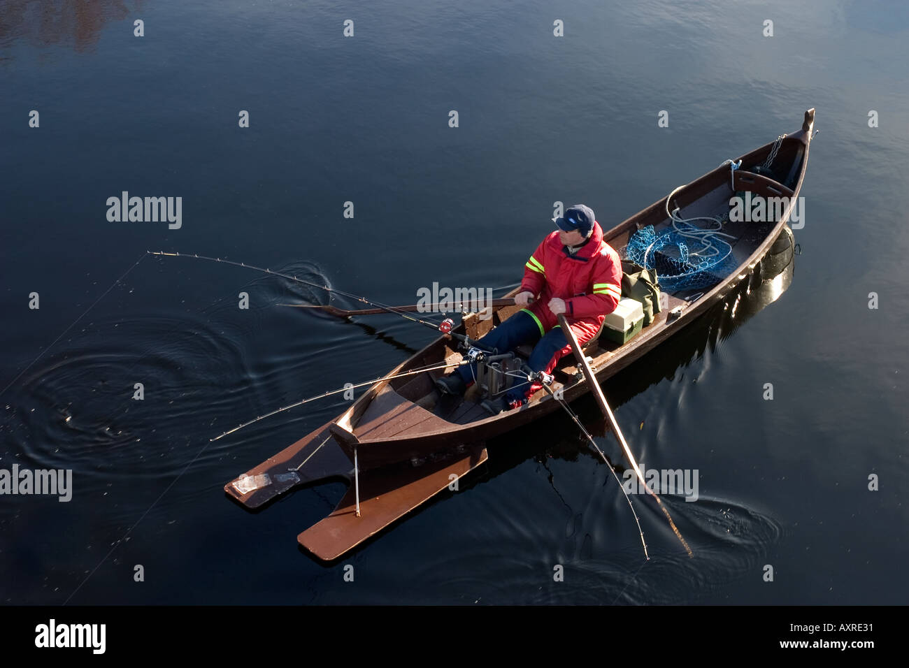 Fischer Trolling mit einem traditionellen hölzernen Ruderboot / Schiff am Fluss Oulujoki, Finnland Stockfoto