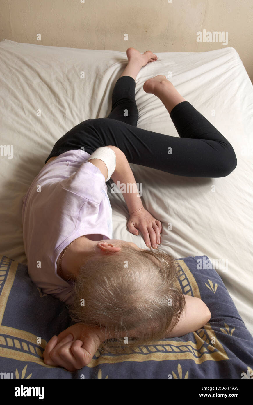 Unwohl Frau Ausübung ihr Bein auf ihrem Bett zwischen Chemotherapie-Behandlungen Stockfoto