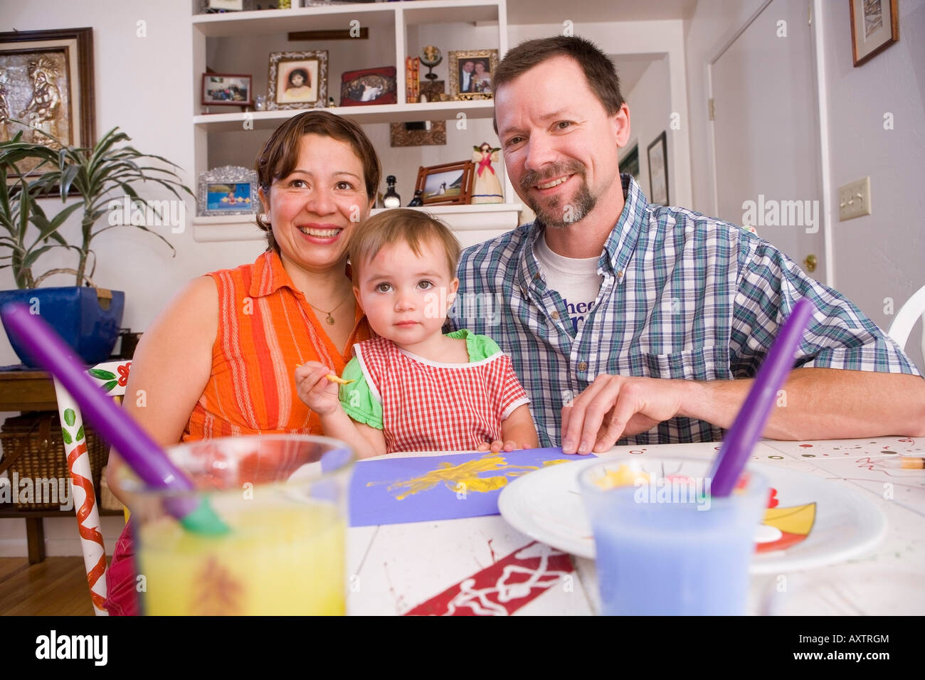 Zwei Jahre altes Mädchen malen mit Farben Poster am Küchentisch mit zwei Eltern helfen Alaska USA Stockfoto