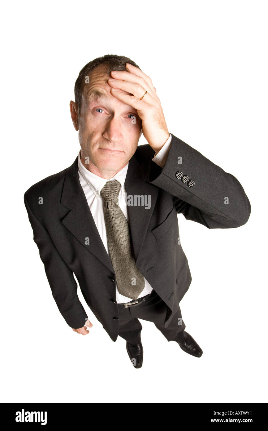Geschäftsmann, der in einem schwarzen Anzug mit der Hand auf der Stirn steht und einem Problem gegenübersteht. Die Aussicht ist von oben nach unten. Stockfoto