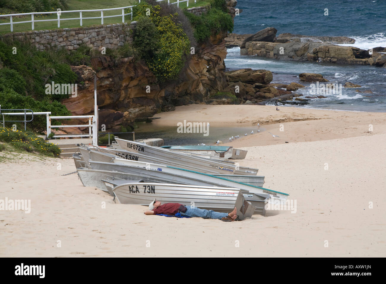 Man ruht neben Jollen auf Coogee Beach, Östliche Vororte, Sydney, Australien Stockfoto