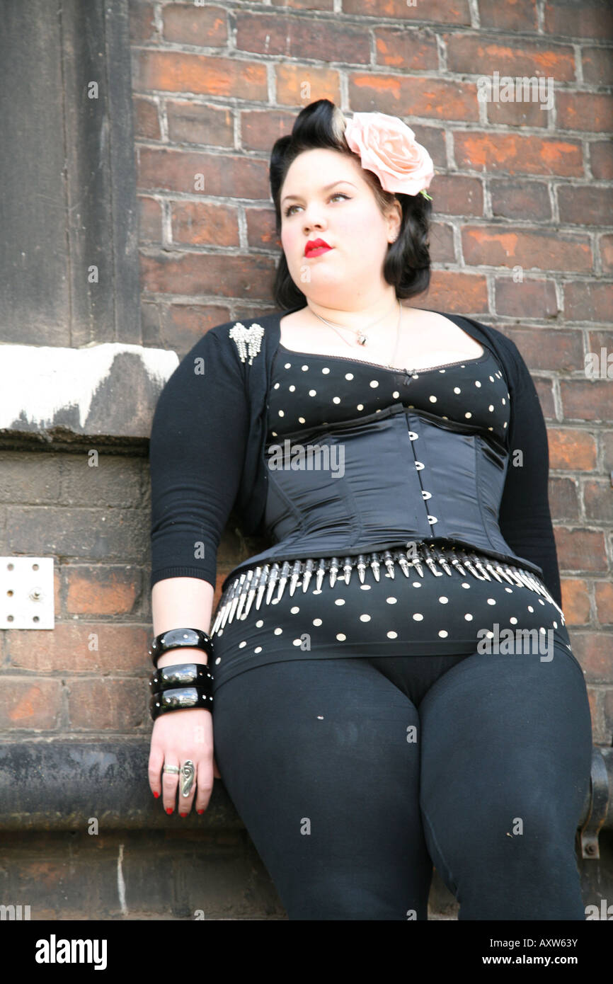 Eine junge dicke Mädchen stehen vor einer Ziegel Wand posiert für Kamera UK