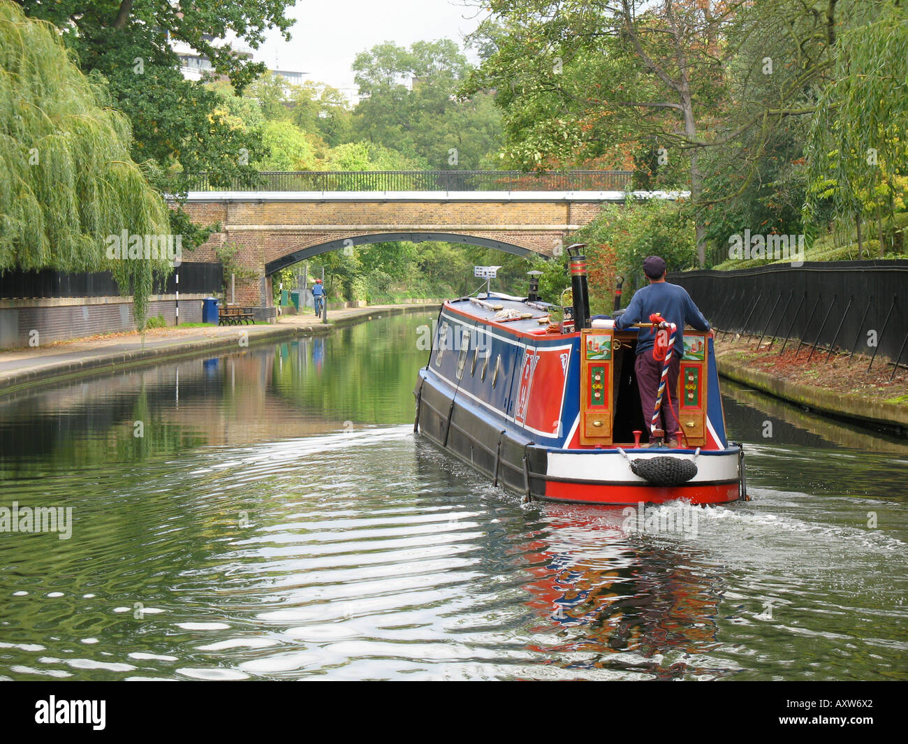 Ein Mann steuert ein Narrowboat über die Regents Canal London England Stockfoto