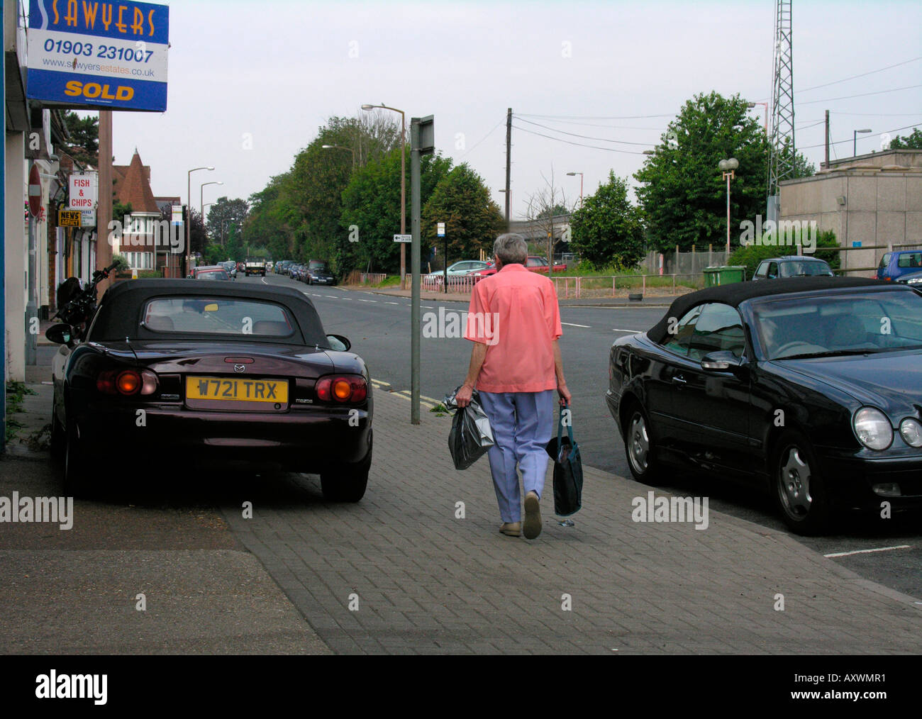 ältere Frau zu Fuß zurück zum geparkten Auto mit Einkaufstüten West Worthing West Sussex Stockfoto