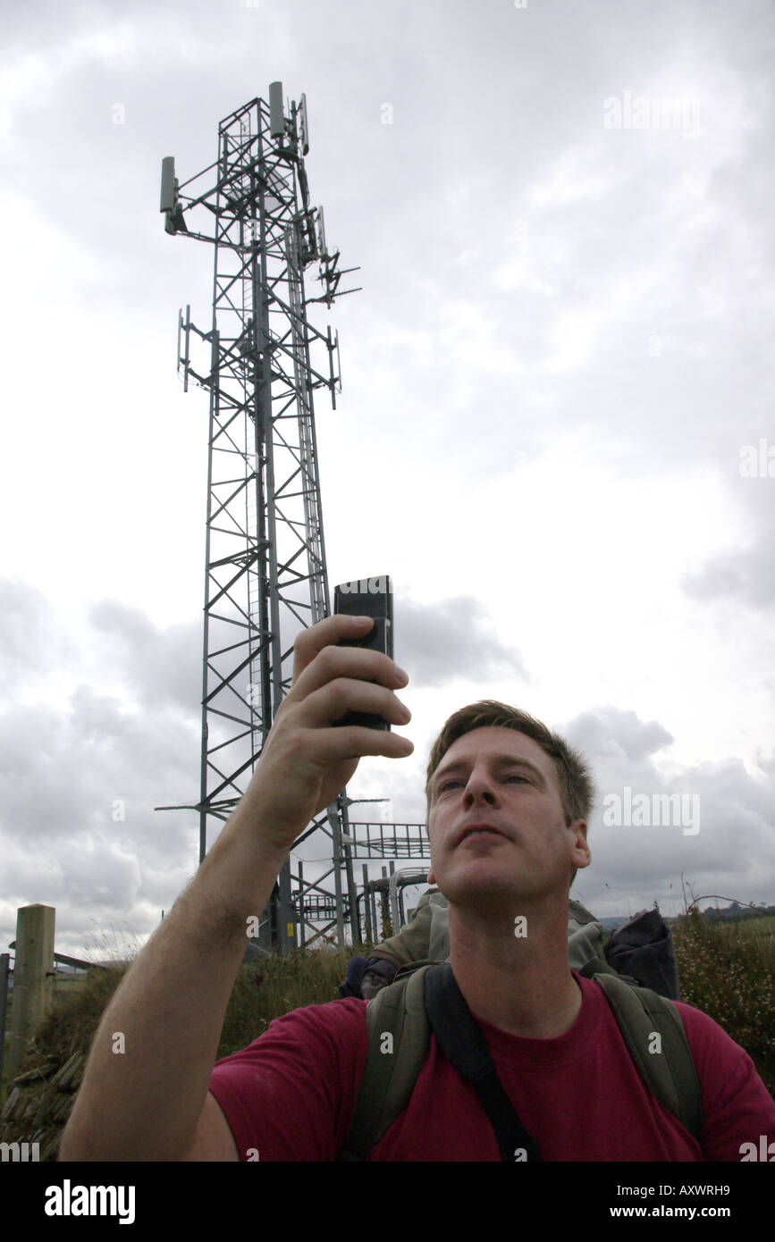 Ein junger Mann komisch Überprüfung Handysignal neben Handy-Master in Cornwall Stockfoto