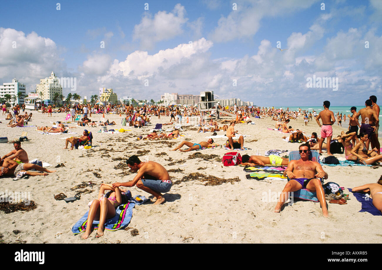 Menschen zum Sonnenbaden am Strand von Miami zeigt Art-Déco-Gebäude am Ocean Boulevard hinter. Florida, USA Stockfoto