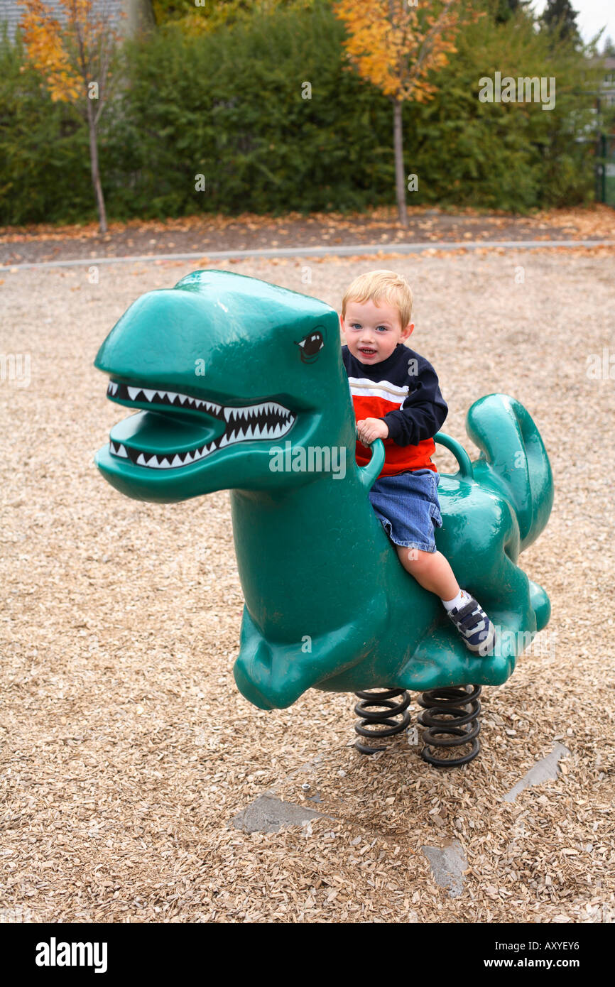 Zwei Jahre alte junge Reiten Dinosaurier Spielzeug im Park. Stockfoto