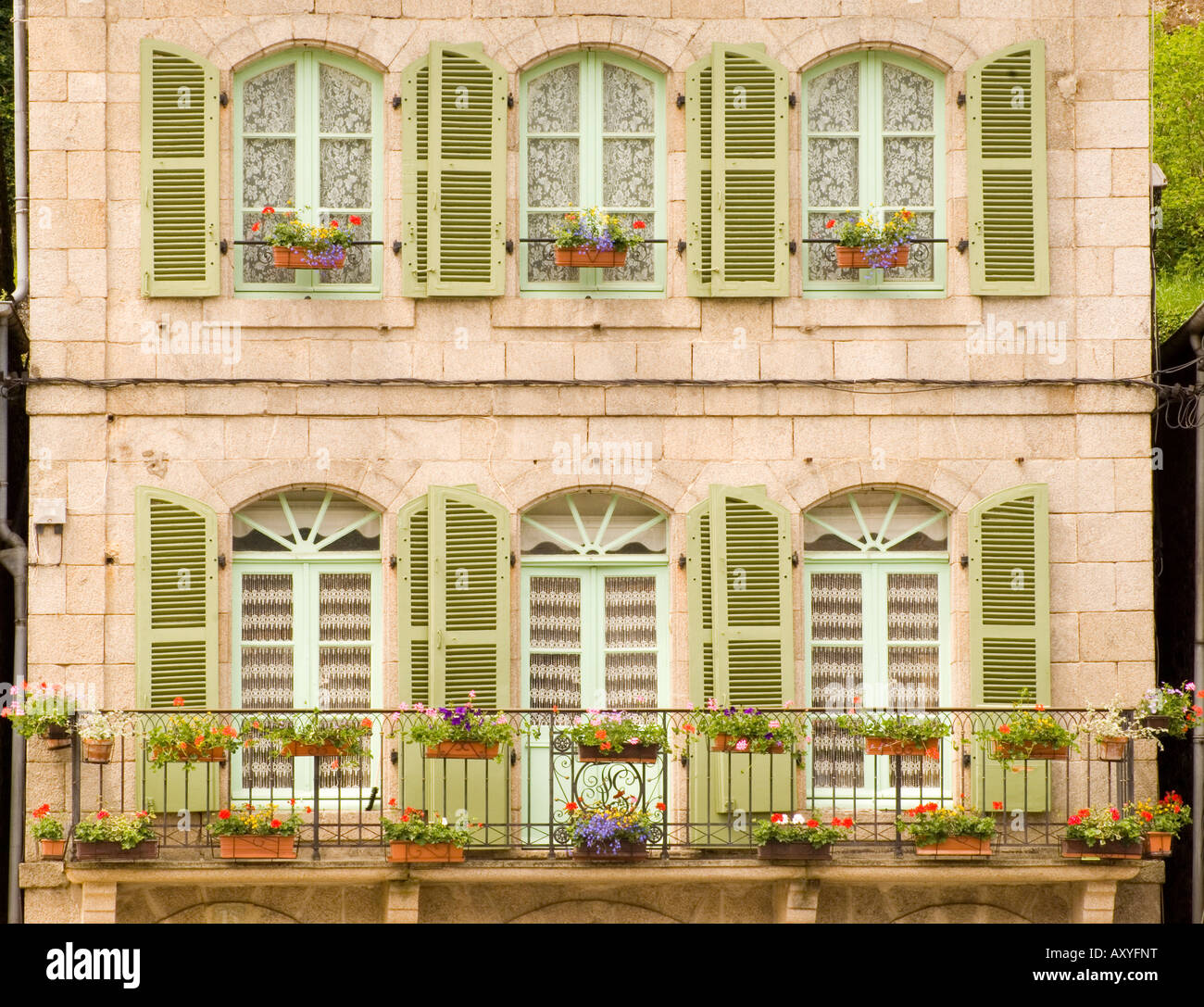 Bunte grüne Fensterläden aus Holz und Blumen bedeckt Balkon auf alten Steingebäude in Dinan, Bretagne, Frankreich, Europa Stockfoto