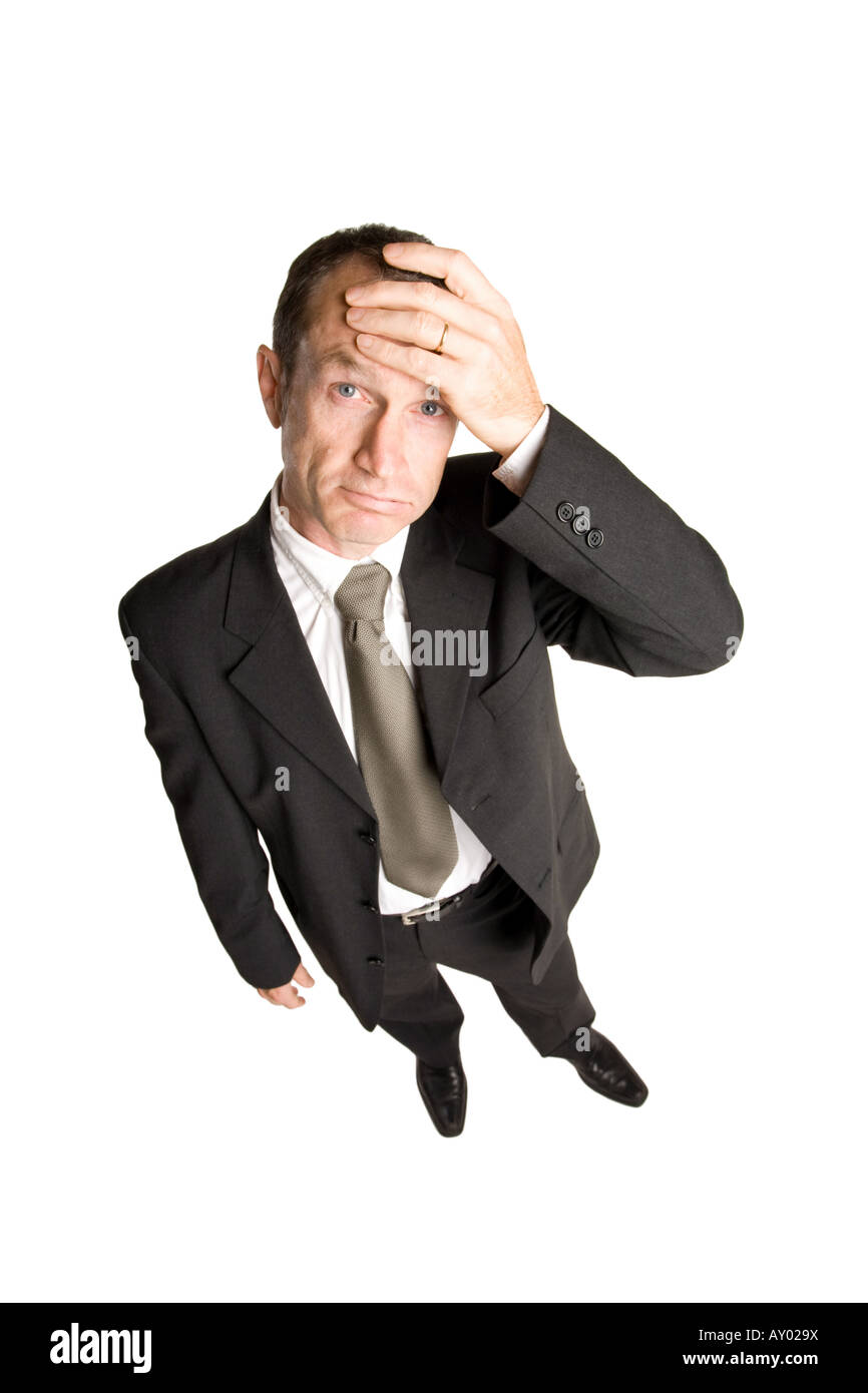 Geschäftsmann, der in einem schwarzen Anzug mit der Hand auf der Stirn steht und einem Problem gegenübersteht. Die Aussicht ist von oben nach unten. Stockfoto