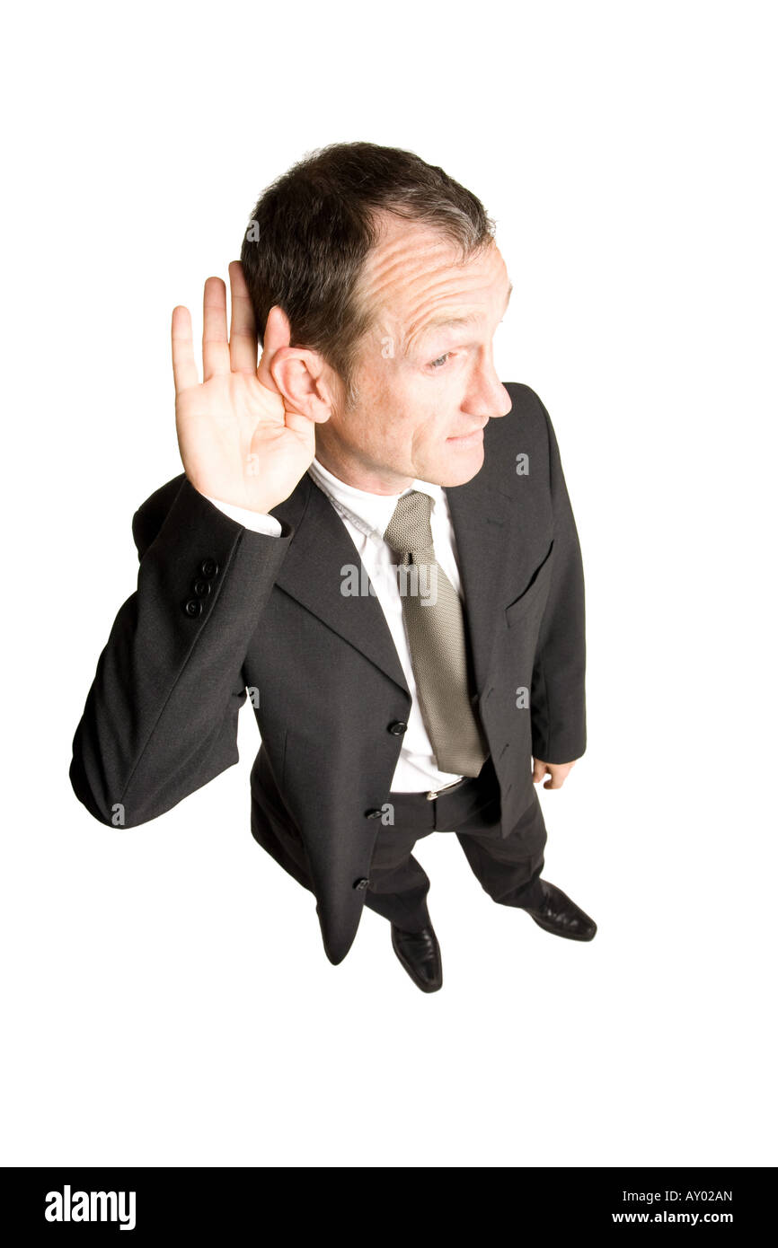 Geschäftsmann, der in einem schwarzen Anzug steht und mit der Hand am Ohr zuhört. Die Aussicht ist von oben nach unten. Stockfoto