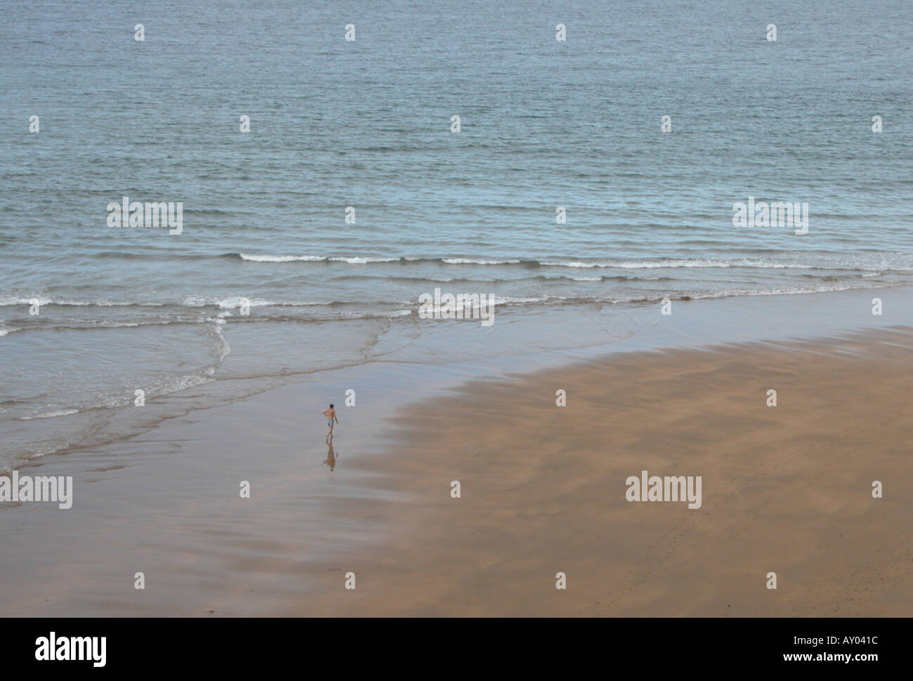 ein einsamer Mann geht an einem Strand am Lekeitio in der baskischen Region von Spanien Stockfoto