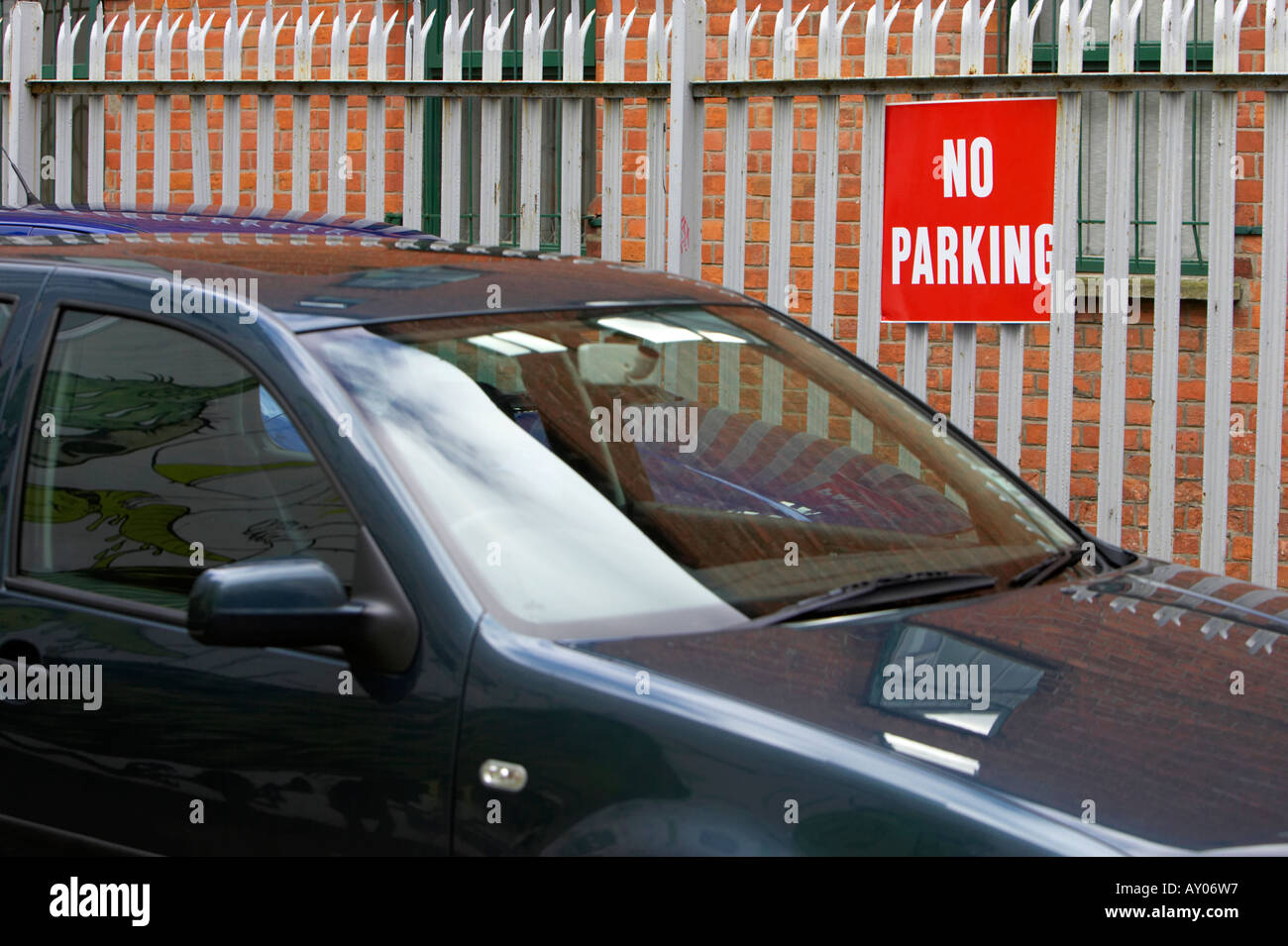 dunkelblaues blaues Auto parkte vor einem roten Metalltor in Cathedral Quarter in Belfast City Centre kein Parkplatz Zeichen zugeordnet Stockfoto