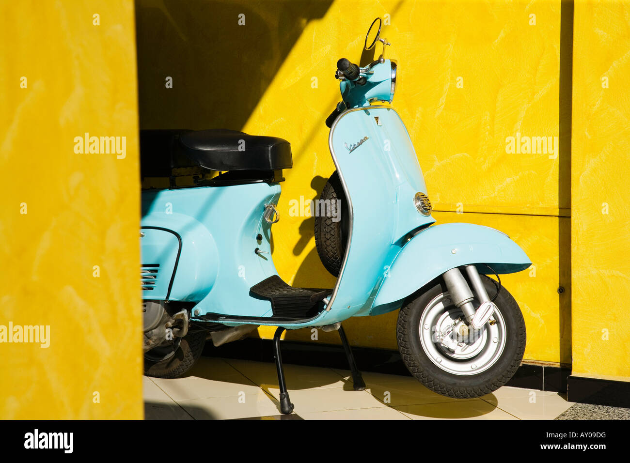 Sardinien blaue Vespa-Roller auf gelbem Hintergrund, eine italienische Ikone. Stockfoto