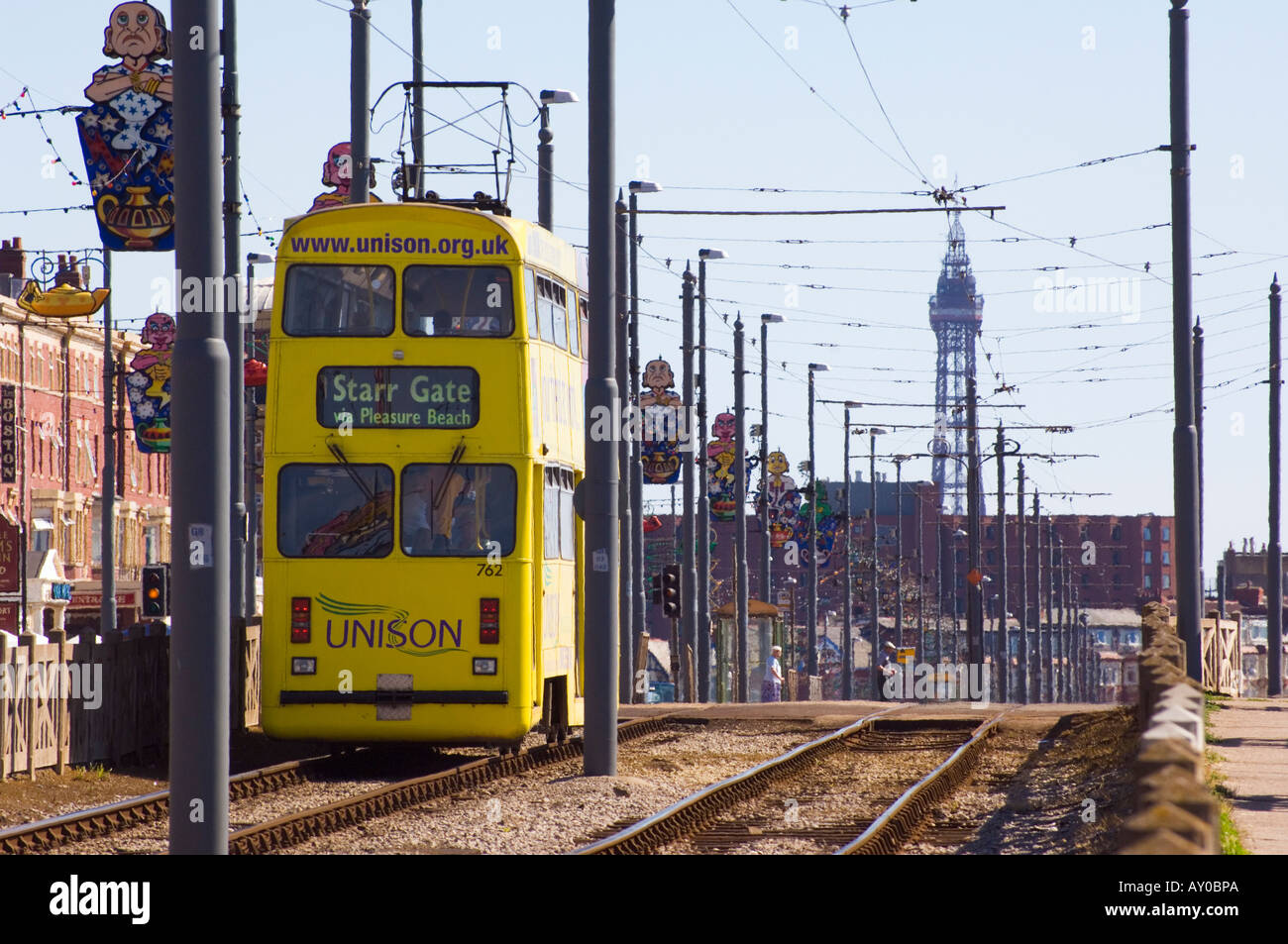 Gelben Straßenbahn gesponsert von Gewerkschaft Unison auf Großbritannien s älteste Straßenbahn in Blackpool mit Blackpool Tower in der Ferne Stockfoto