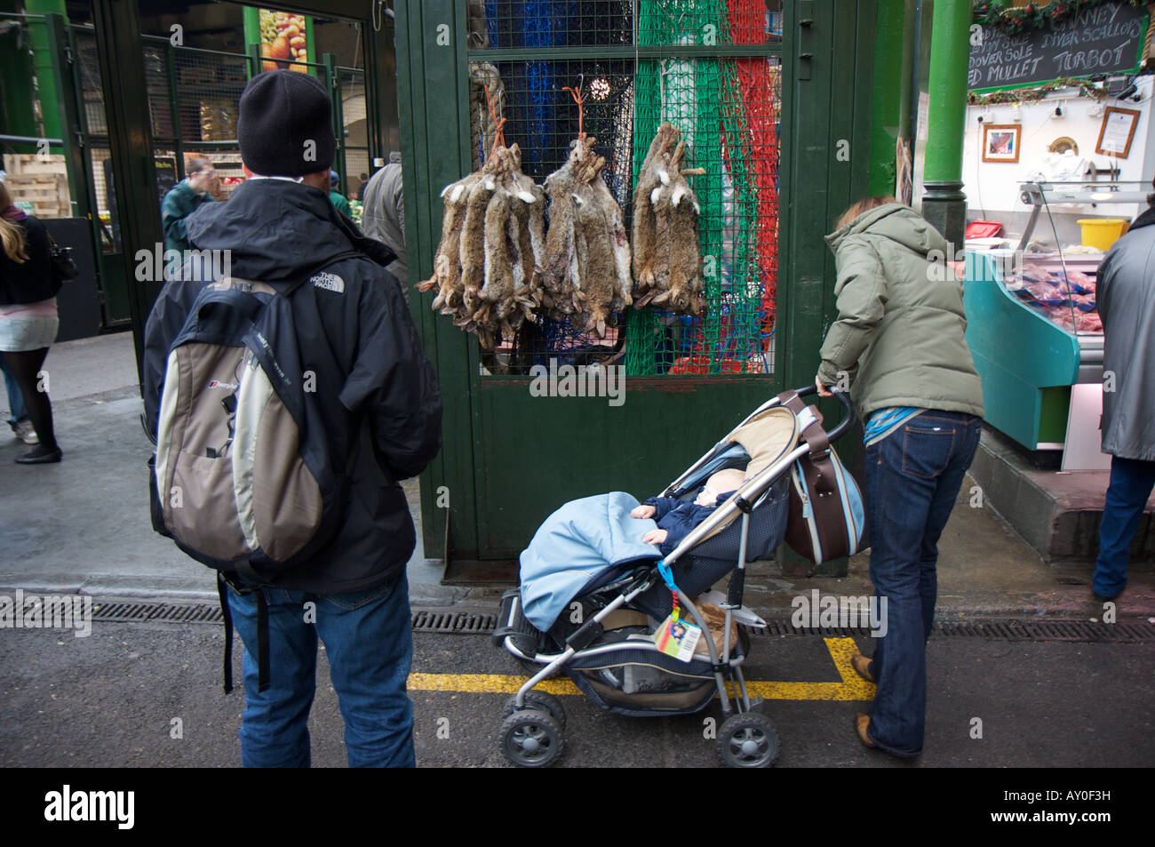 Ein Mann von Hasen zu verkaufen neben eine Frau und Ihr Baby in der Londoner Borough Market gebannt Stockfoto