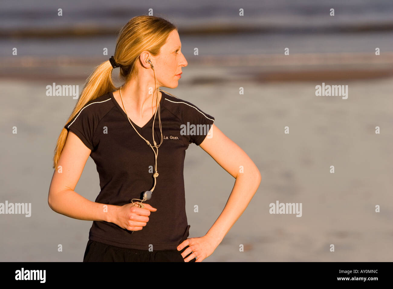 Junge Frau, die Ausübung am Strand anhören von MP3-player Stockfoto