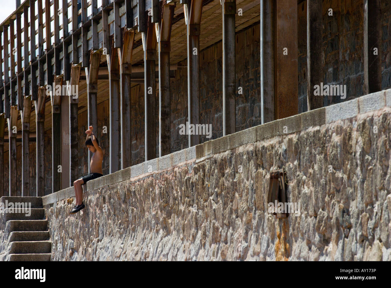 Junge sitzt unter Eisenbahn Bridgeon Strand in Dawlish, Devon Stockfoto