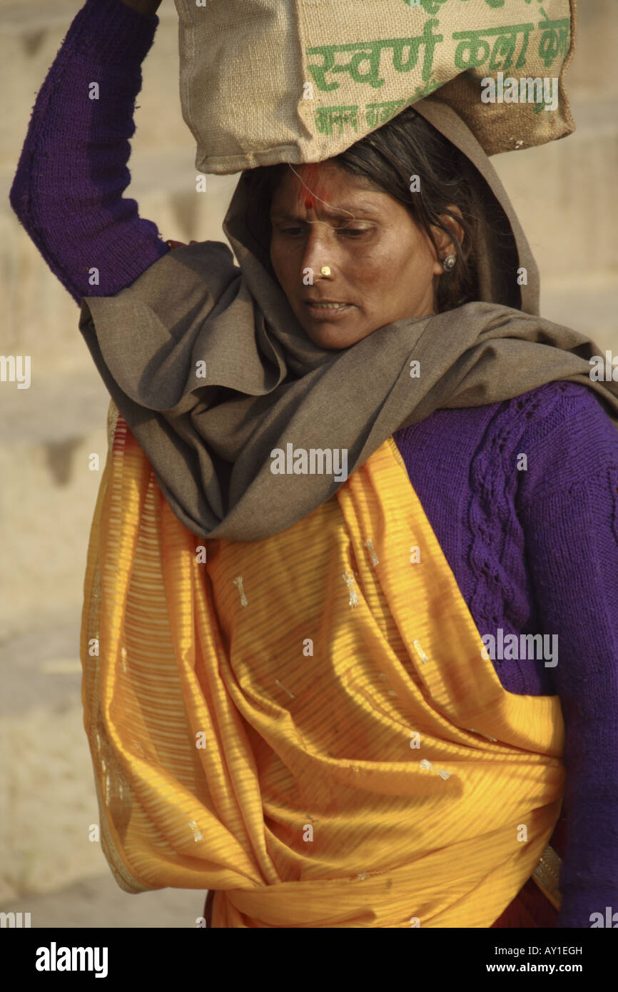 Eine indische Frau balanciert gekonnt ihre Bestimmungen auf dem Kopf in Varanasi, Uttar Pradesh, Indien Stockfoto