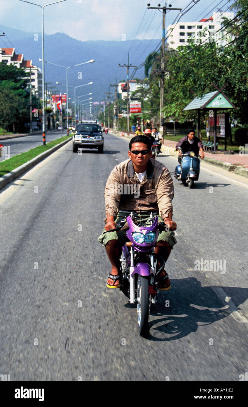 Thailand, Provinz Chiang Mai, Nordthailand, Chiang Mai - Motorradfahrer fahren in Chang Mai mit Auto im Hintergrund. Stockfoto